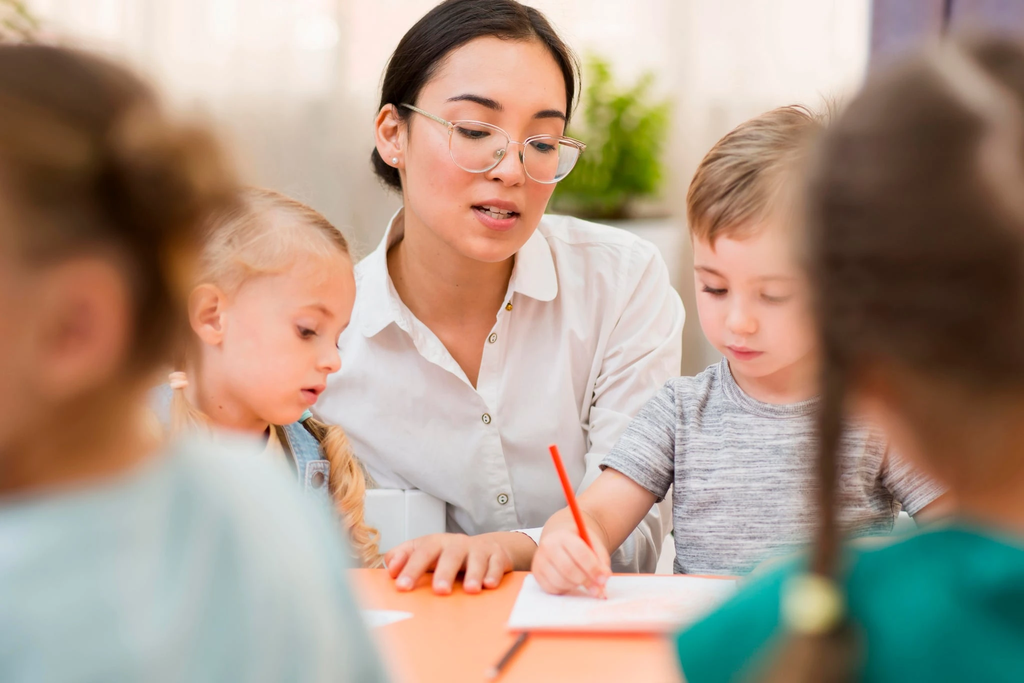 A teacher working with young students at a classroom table